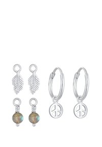 Orecchini a cerchio in argento con ciondoli a forma di simbolo della pace, accompagnati da stud a forma di foglia e accenti di perline. Finiture texturizzate e lucidate.