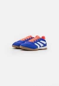 Zapatillas deportivas azules con cordones naranjas, acentos blancos y un upper texturizado. Presentan una suela de goma y un diseño transpirable.