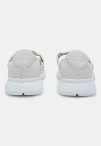 Jasno-beżowe sneakersy z gładką skórzaną cholewką, zaokrąglonym tyłem, miękkim wsparciem kostki i grubą białą gumową podeszwą. Minimalistyczny design.