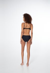 Čierny bikiny set s textúrovanými pásmi, nastaviteľnými ramienkami a stredným pokrytím chrbta. Jednoduchý dizajn bez viditeľných kovových akcentov.