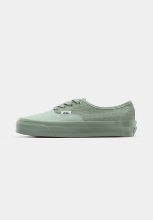 Zapatillas de lona verde con un panel lateral texturizado, punta redonda, suela de goma y cierre de cordones con seis ojales.
