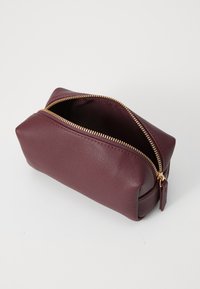 Burgundy leather pouch with a textured surface, gold zipper closure, and a rectangular shape, open at the top to reveal the interior.