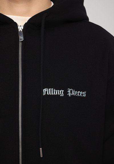 Hanorac negru cu fermoar, realizat dintr-un material moale, având brodat în argint "Filling Pieces". Include fermoar argintiu și accente cu șnur.