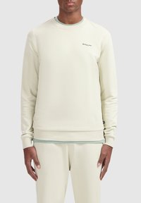 Lichtbeige sweatshirt met geribde manchetten en zoom, voorzien van een ronde hals en een subtiele "BALLIN'" logo in donkergrijs op de borst.