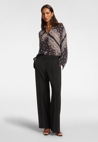Pantalones de pierna ancha negros combinados con una blusa estampada que presenta tonos de azul oscuro y blanco, mostrando diseños de paisley y flores.