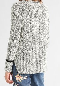 Ribbad tröja i grått och vitt med strukturerat mönster, har svarta detaljer vid ärmslut och sidopartier för ökad rörelsefrihet.