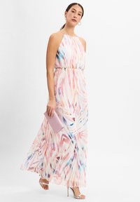 Maxikleid mit fließender Silhouette, ausgestattet mit einem pastellfarbenen abstrakten Muster in Rosa, Blau und Weiß. Metallische Absatzschuhe und eine rosa Clutch.