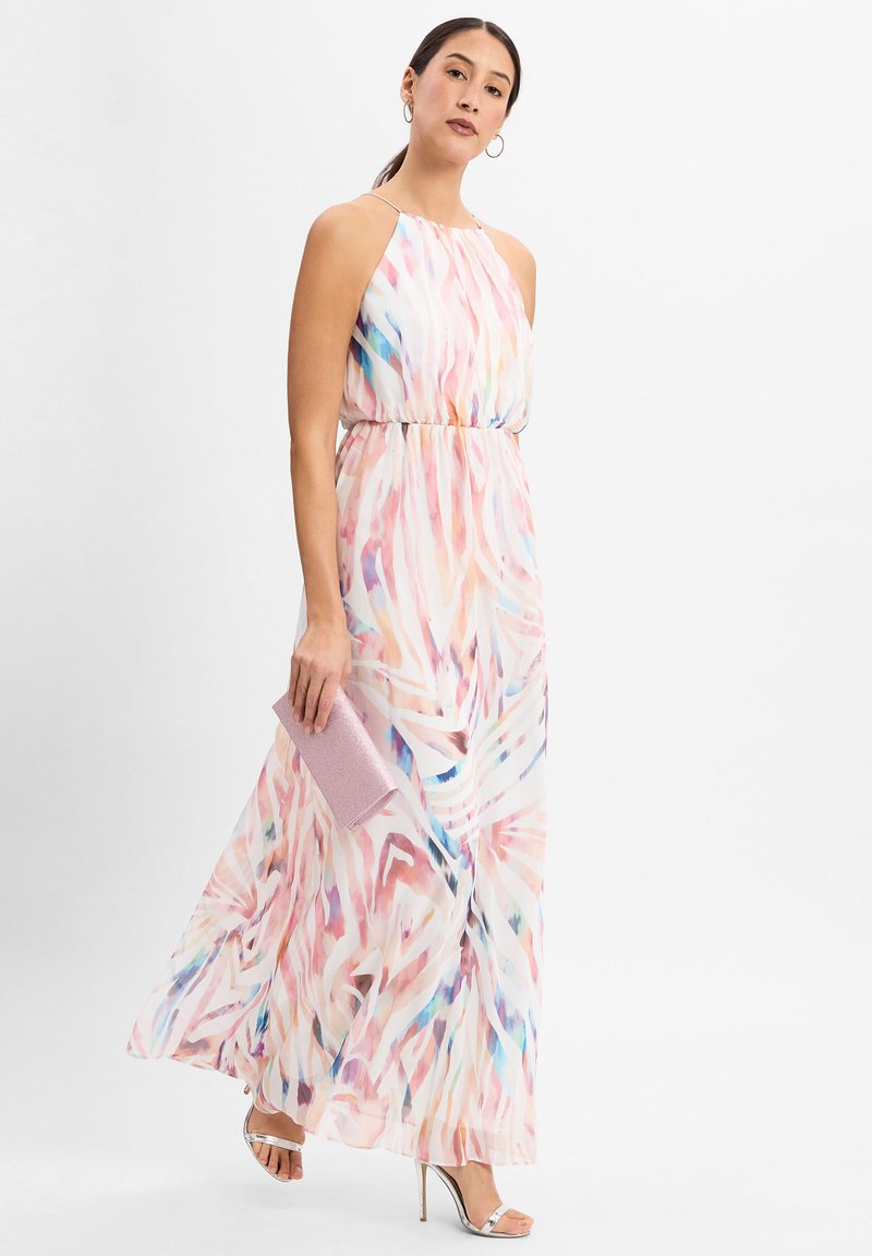 Maxikleid mit fließender Silhouette, ausgestattet mit einem pastellfarbenen abstrakten Muster in Rosa, Blau und Weiß. Metallische Absatzschuhe und eine rosa Clutch.
