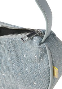 Bolso de denim en azul claro con acentos de cristales de imitación plateados, cremallera plateada y asa gris. Presenta un tejido texturizado y una etiqueta amarilla en contraste.