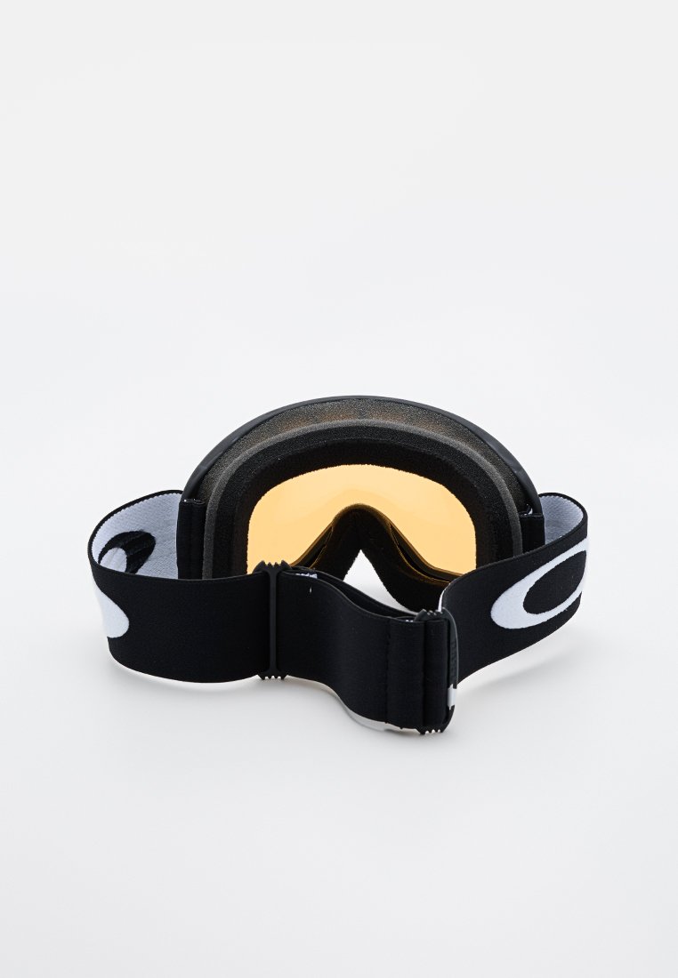 Gogle narciarskie z bursztynowymi soczewkami, czarną piankową wyściółką i regulowanym czarnym paskiem z białym logo na jednolitym białym tle.