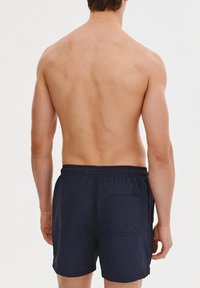 Granatowe szorty kąpielowe z elastycznym pasem i tylną kieszenią. Wykonane z lekkiego materiału, charakteryzujące się miękką teksturą i casualowym designem.