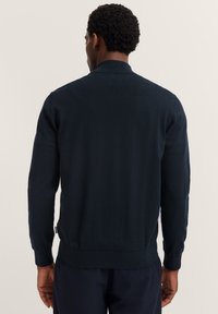 Cardigan lavorato a maglia blu navy con colletto e polsini a coste, presenta una vestibilità dritta e una texture morbida. La vista posteriore mostra dettagli di design minimi.