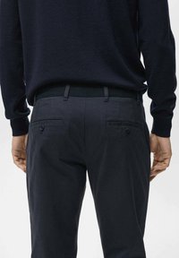 Marineblaue Hose mit glatter Textur, ausgestattet mit einem taillierten Bund, zwei Gesäßtaschen mit Knopfverschluss und einem geraden Bein-Schnitt.