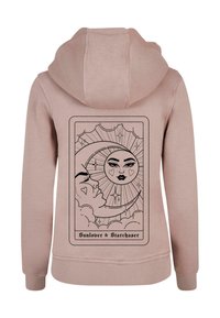 Rosa hoodie med en stor svart grafik på baksidan, med en design av sol och måne med intrikata detaljer och texten "Sunlover & Starchaser."