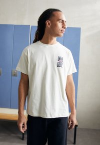 Weißes Baumwoll-T-Shirt mit einem Grafikdruck "FIND YOUR LINE" in Schwarz und Pink auf der linken Brust, mit kurzen Ärmeln und entspannter Passform.