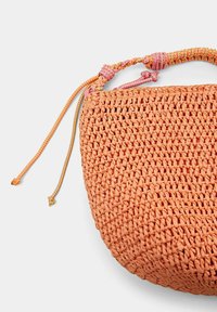 Oranje geweven tas met een ronde vorm. Heeft een gestructureerde afwerking en een kleurrijke gevlochten draagband met twee verstelbare trekkoorden.