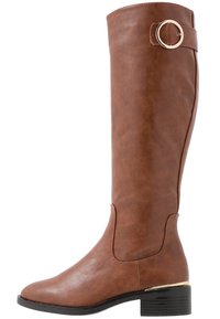 Botte marron montant jusqu'au genou en cuir synthétique texturé, avec un bout rond, un talon carré bas et un accent circulaire doré sur la bride.