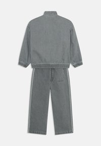 Set composto da giacca e pantaloni in denim grigio. Presenta polsini e cintura elasticizzati, tasche laterali e strisce laterali a contrasto. Texture liscia.