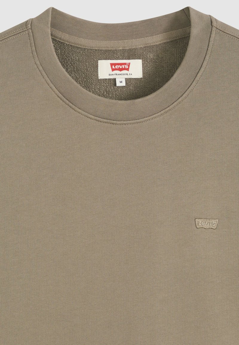 Beiges Levi's Sweatshirt mit Rundhalsausschnitt, geripptem Kragen, sichtbarem Levi's-Logo-Patch auf der Brust und Größenetikett M im Innenkragen.