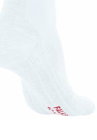 Biała sportowa skarpetka pokazana z boku, z fakturowaną powierzchnią i czerwonym nadrukiem na dole. Tło jest gładkie i białe.