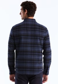 Herren-Flanellhemd in dunkelblauem und schwarzem Karomuster, mit einem Button-Down-Kragen, langen Ärmeln und einem abgerundeten Saum mit Knopfmanschetten.