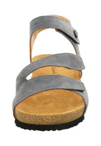 Grijze suède sandaal met drie brede banden die de voorkant kruisen, een cognackleurige gevoerde binnenzool en een zwart, gestructureerd loopvlak. Verstelbare gesp aan de zijkant.