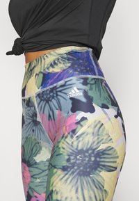 Leggings con motivo floreale in una combinazione di verdi, rosa e blu. Realizzati in tessuto elasticizzato con il logo Adidas sulla vita.