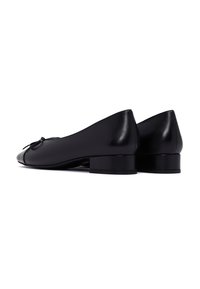 Ballerine in pelle nera con punta arrotondata, piccolo tacco a blocco e fiocco decorativo nella parte anteriore. Tessuto liscio e design minimalista.