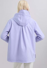 Chaqueta impermeable de lavanda clara con capucha, de corte holgado, textura suave y detalle plisado en la parte trasera.