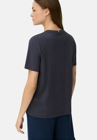 Mørkegrå kortærmet t-shirt i glat stof, med rund halsudskæring og en diskret detalje på ryggen, parret med navy bukser.