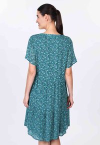 Grünes Kurzarmkleid mit floralem Muster, lockerer Passform und gerafftem Taillenbereich, mit einem Saum, der hinten bis zur Mitte der Waden reicht.