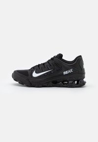 Zapatilla de running Nike Reax negra con parte superior de malla y sintético, suela de goma, detalle texturizado, collar acolchado y logotipo Swoosh prominente.