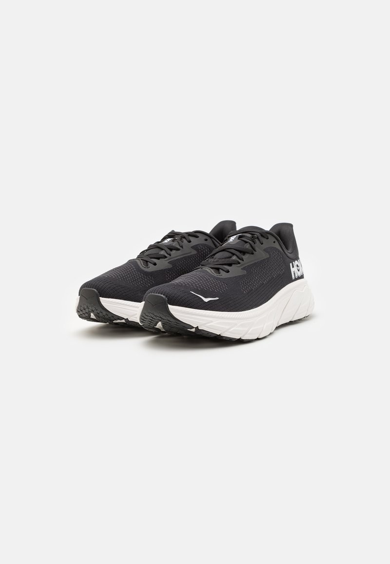 Czarne buty do biegania z teksturowaną siateczkową cholewką, białą podeszwą pośrednią i gumową podeszwą zewnętrzną. Zawierają sznurówki i logo z boku.