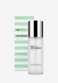 Bouteille en verre transparent avec un capuchon de pompe argenté. Boîte rayée verte et blanche avec du texte noir, étiquetée comme BIOEFFECT EGF Essence, 100ml.