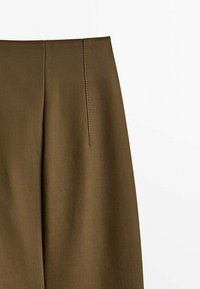 Olive green trousers with a smooth texture, featuring a flat front and vertical pleat detail along the waistband.
