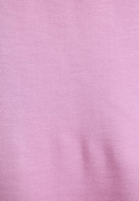 Tela de algodón de color rosa claro con una textura suave, que presenta un color sólido y consistente, y una ligera elasticidad en la superficie.