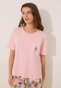 T-shirt rosa a maniche corte realizzata in morbido tessuto, con taschino decorato da ricamo di un cactus verde e la scritta "le jardin."
