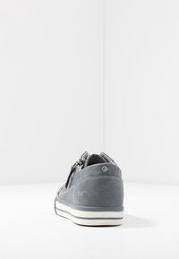 Sneaker in pelle grigia con finitura texturizzata, punta rotonda, chiusura con zip e suola in gomma bianca con strisce blu. Loghi visibili di lato.