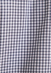 Tkanina w biało-granatową krateczkę z gładką fakturą i jednolitym wzorem siatki.