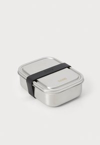 Lunchbox ze stali nierdzewnej w kształcie zaokrąglonego kwadratu, z czarnym silikonowym paskiem i wytłoczonym logo na wieczku. Elegancka, metaliczna wykończenie.
