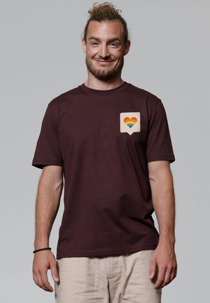 Maroon cotton t-shirt with short sleeves and a crew neck, featuring a multicolored heart icon on a white speech bubble on the chest.