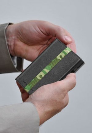 Black leather wallet with a green and light green patterned elastic band. Smooth texture, rectangular shape, held in a hand.