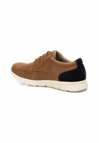 Zapato de gamuza marrón con acentos de gamuza azul marino, punta redonda, seis ojales y una suela de goma blanca con ranuras horizontales.