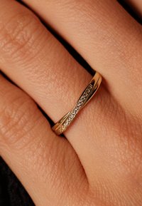 Goldring mit einem gedrehten Design, das eine Reihe von kleinen Diamanten auf einer Seite aufweist. Glatte Oberfläche und polierte Textur.