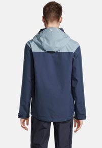 Teknisk jacka med en tvåfärgad design som har en mörkblå kropp och en ljusblå huva. Tillverkad av vattentåligt material, designad för utomhusbruk.