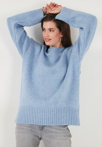 Světle modrý oversized svetr vyrobený z měkké, texturované pleteniny. Má široké žebrované manžety a lem, s volným střihem.