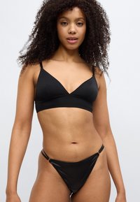 Σετ μαύρου εσωρούχου με τριγωνικό σουτιέν με λεπτές τιράντες και αντίστοιχα σλιπ μπικίνι με ψηλό κόψιμο. Λείο ύφασμα με ελάχιστες ραφές.