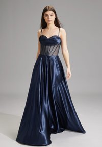 Abito da sera blu navy con corpino aderente, pannelli in rete trasparente e gonna in satin fluente. Presenta spalline sottili e una texture a strati.