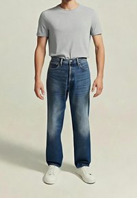 T-shirt gris clair à col rond associé à un jean bleu droit avec une finition délavée et des baskets blanches. Design simple, sans motifs.