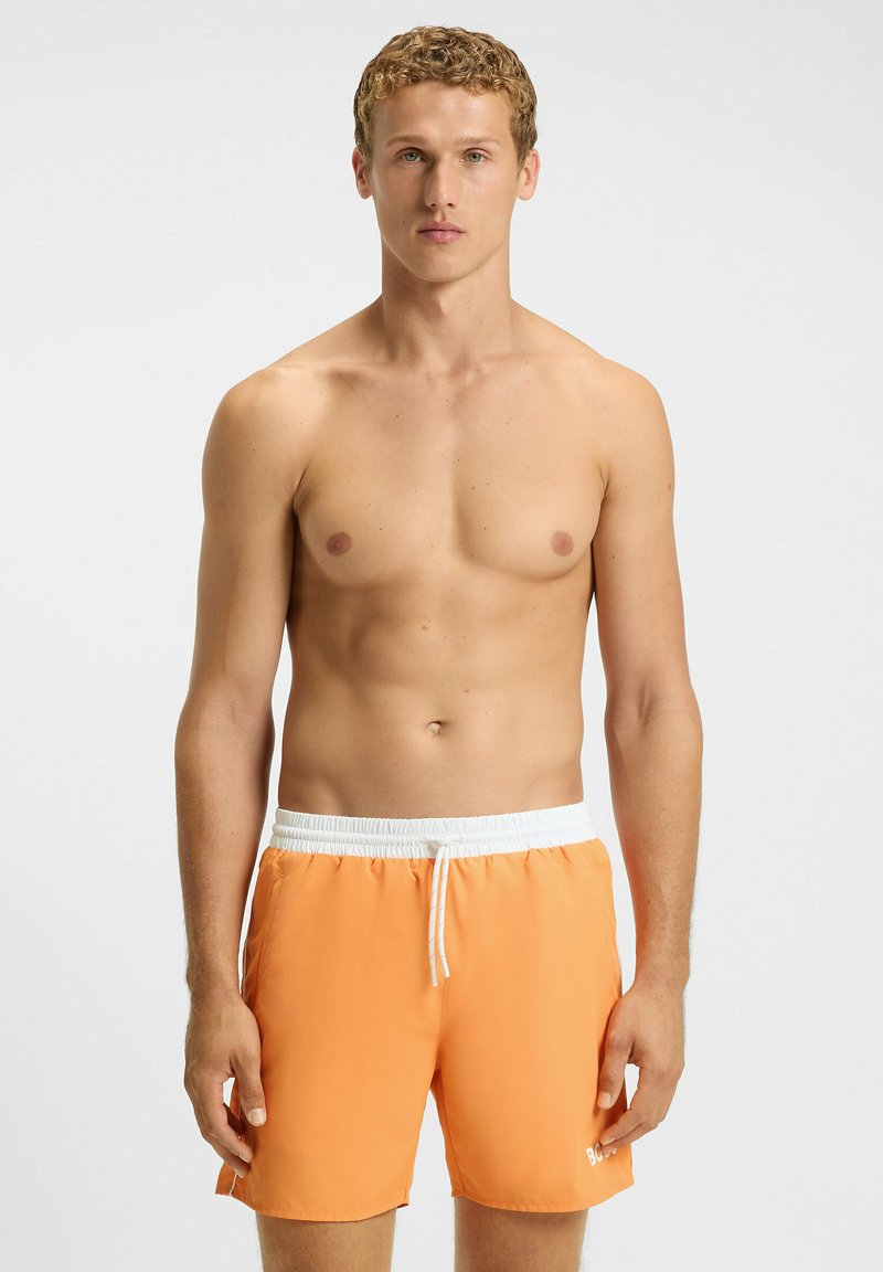Heren zwemshorts in fel oranje met een witte elastische tailleband en trekkoord. Glad van textuur, knielang, met zijzakken.